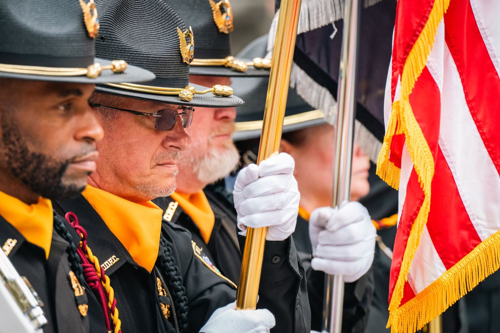 An honor guard in white gloves presenting the American flag at a ceremony
